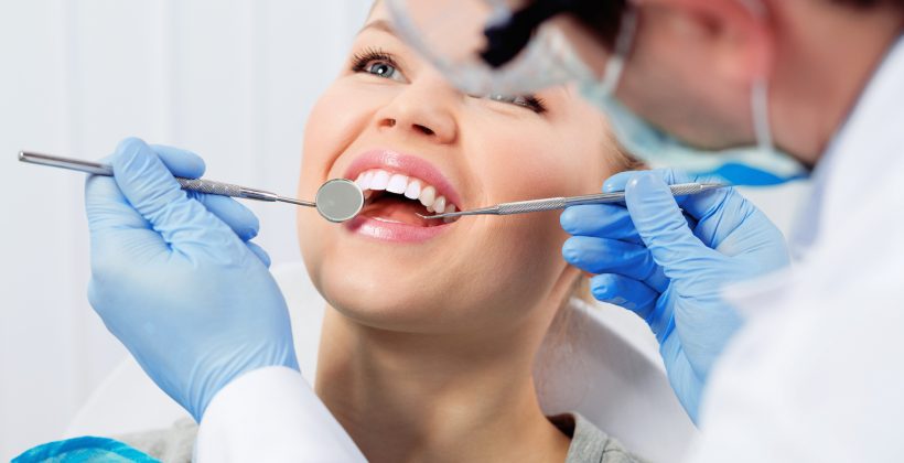 dentist looking at woman's mouth during checkup