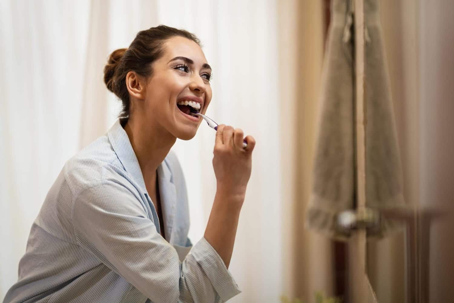 woman brushing her teeth with a smile
