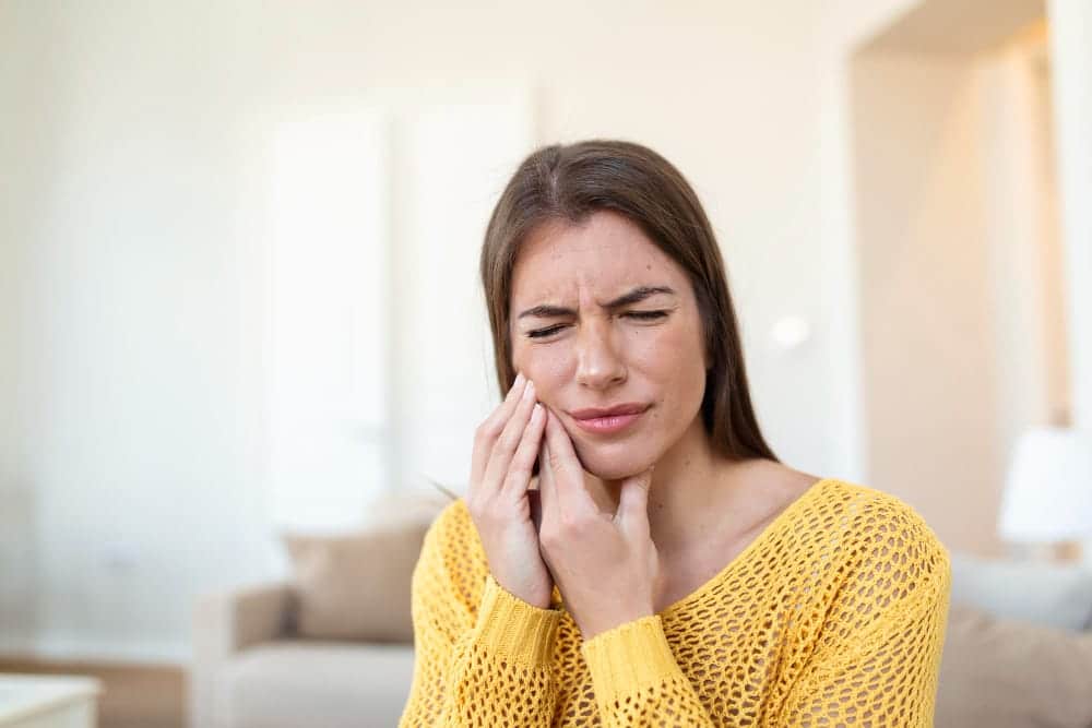 woman holding the right side of her jaw in pain