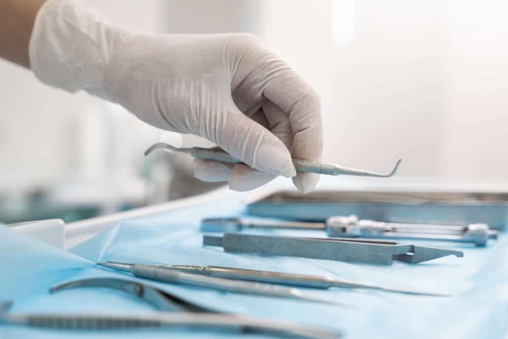 hand with white glove on holding dental utensil