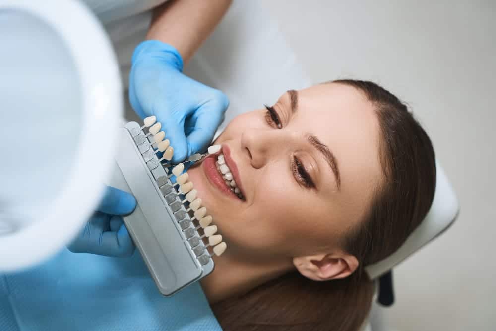 A dentist and patient reviewing veneer options on a dental model, focusing on the selection process.