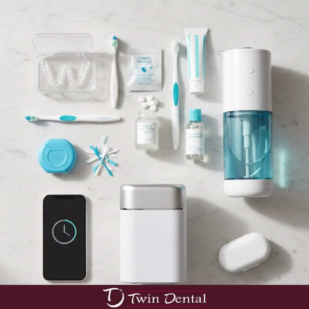 Flat lay of Invisalign care essentials including clear aligner trays, toothbrushes, cleaning crystals, antibacterial soap, floss, cotton swabs, a portable case, ultrasonic cleaner, and smartphone on a marble surface.